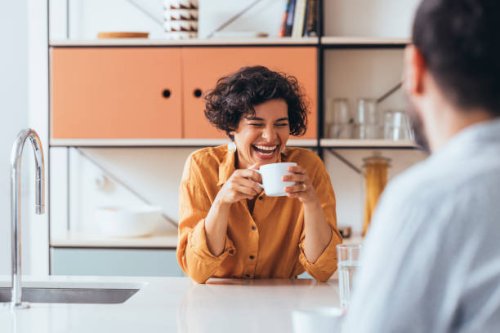 a happy couple drinking tea in the kitchen, talking and laughing - coffee stock pictures, royalty-free photos & images