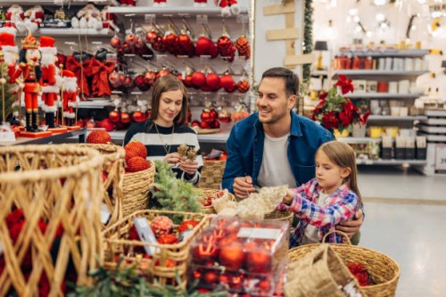 a little girl chooses christmas decorations with her parents. they look at the selection of decorations that are on display in the department store - home decoration stock pictures, royalty-free photos & images