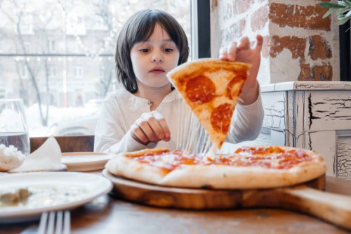 a little girl eats pizza in a pizzeria. the cute girl eats pizza with an appetite. - junk food stock pictures, royalty-free photos & images