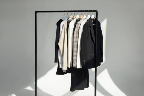 a lot of different wardrobe clothes hang on hangers on a rail. concept for selling clothes. - fashion stock-fotos und bilder