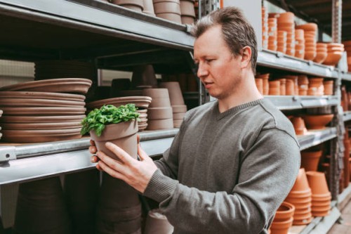 a male gardener chooses a pallet for a home flower in a flower shop or mall. gardening at home as a hobby for men. home gardening - garden decoration stock pictures, royalty-free photos & images
