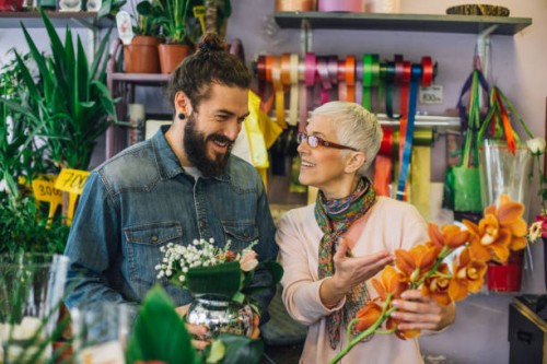 a man and a woman holding flower arrangements at a flower shop - garden decoration stock pictures, royalty-free photos & images