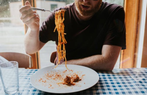 a man eats a plate of spaghetti bolognese with meatballs at a dining table - food stock pictures, royalty-free photos & images