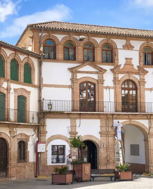 a man standing on a ladder, painting a historic building at plaza ochavada archidona. - home decoration stock pictures, royalty-free photos & images