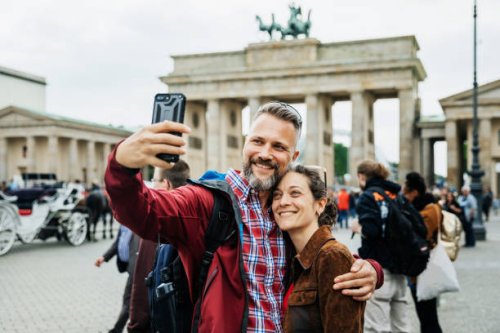 a mature couple take a selfie together in front of brandenburg gate in berlin - travel stockfoto's en -beelden
