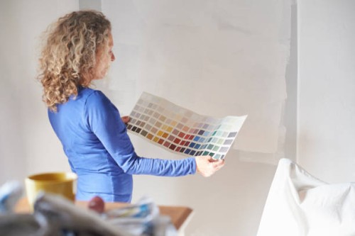 a mature woman studying a paint colour swatch - home decoration stockfoto's en -beelden