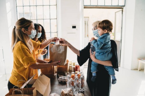 a mother with her little son is taking a bag of food at the food and clothes bank - food stock pictures, royalty-free photos & images