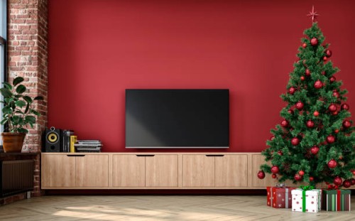 a nostalgic retro living room with with a tv on a cabinet in front of a red plaster wall and partly ruined brick wall and christmas decoration - home decoration stock pictures, royalty-free photos & images