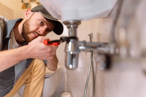 a plumber carefully fixes a leak in a sink using a wrench - home decoration stock pictures, royalty-free photos & images