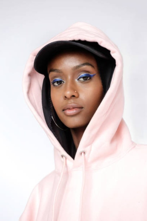 a portrait of a beautiful, young muslim woman wearing a black hijab, black baseball cap and a pink hoodie photographed in studio setting. - fashion stock pictures, royalty-free photos & images