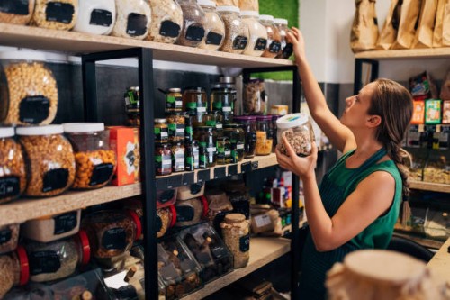 a saleswoman in an organic food store arranges jars of raw food on the shelf - food stock pictures, royalty-free photos & images