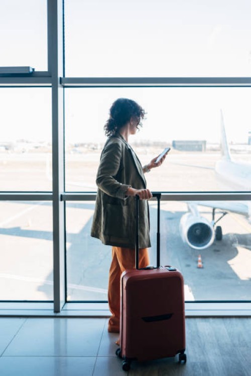 a side view of an unrecognizable busy elegant businesswoman using her mobile phone to talk to her business partners while waiting for her flight - travel stock pictures, royalty-free photos & images