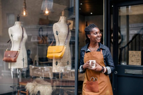 a small business owner stands outside her handbag shop. - fashion stock pictures, royalty-free photos & images