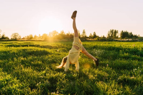 a teenage girl with curly hair dance in a field at sunset. - fashion stock pictures, royalty-free photos & images