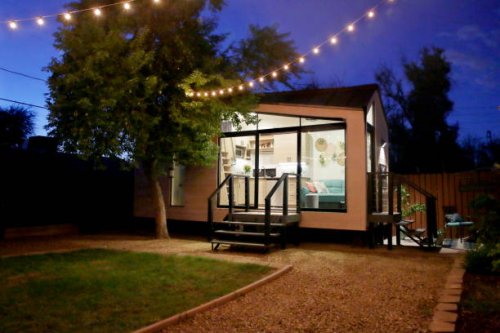 a tiny house with large glass windows, sits in the backyard at night, surrounded by trees and party lights. - garden decoration stock pictures, royalty-free photos & images