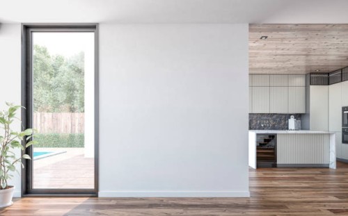 a white blank wall with a window door and garden and patio view in the foreground, a modern light grey kitchen with marble rectangular breakfast kitchen island in the background - garden decoration stock pictures, royalty-fre