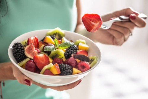 a woman breakfasts a fruit salad high in vitamins and fiber. - food stock pictures, royalty-free photos & images