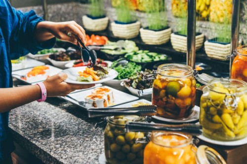 a woman chooses food in a hotel restaurant. a woman takes food from the buffet. - junk food stock pictures, royalty-free photos & images
