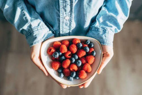 a woman holds a plate of fruits and berries in her hands - food stock pictures, royalty-free photos & images