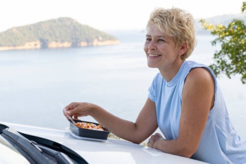 a woman is having lunch outside eating on the car - junk food stock pictures, royalty-free photos & images