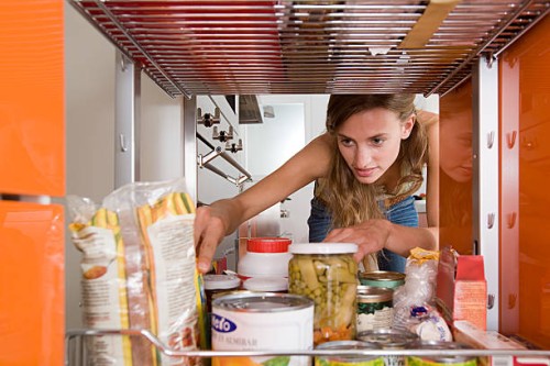 a woman reaching for a packet of food - food photos et images de collection