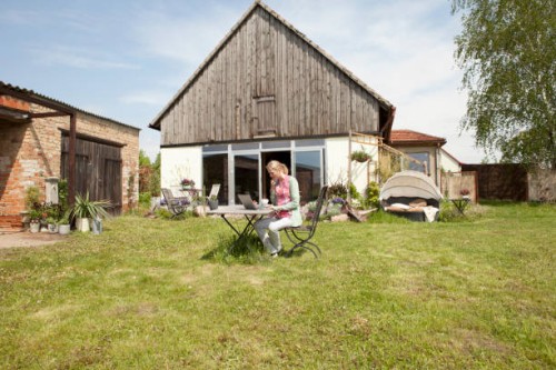 a woman sitting at a table in her backyard using a laptop - garden decoration photos et images de collection