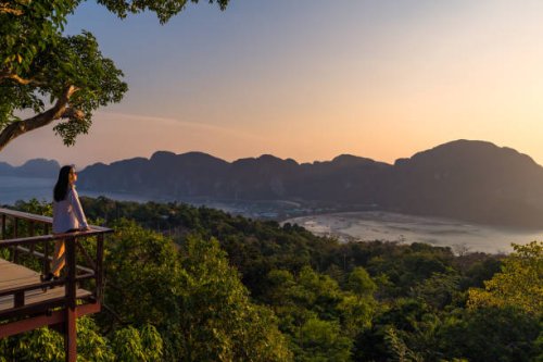 a woman standing at phi phi view point and see the view from a bird's eye view of the mountains, the sea and the sunset. and town on phi phi island, krabi province, thailand - travel stock pictures, royalty-free photos & imag
