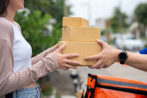 a woman waiting at the door is given food by a smiling delivery man. - junk food stock pictures, royalty-free photos & images