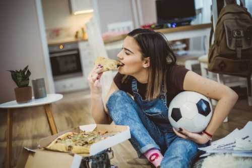 a woman watches football and cheers for her team - junk food stock pictures, royalty-free photos & images
