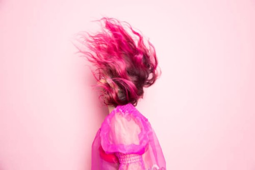 a woman with pink hair throws her head back so that her hair covers her face in front of a pink background - fashion stock pictures, royalty-free photos & images