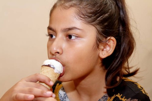 a young beautiful girl eating cone ice cream - junk food stock pictures, royalty-free photos & images
