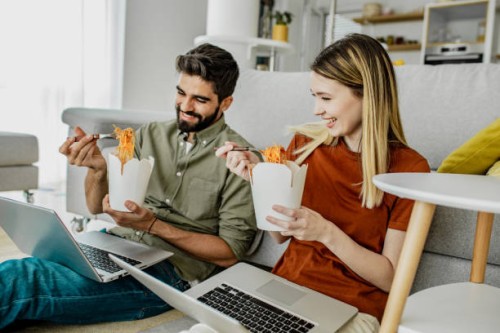 a young couple is working from home and eating pasta - junk food stock pictures, royalty-free photos & images