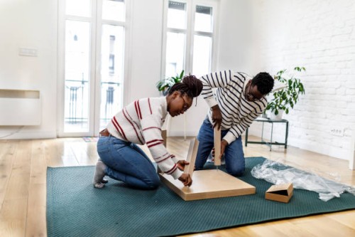 a young couple of afro-americans is assembling new furniture in their house. - home decoration stock pictures, royalty-free photos & images