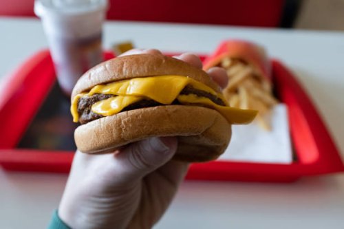 a young man is holding a piece of hamburger in his hands. a guy or a man eats fast food. a hungry skinny guy is eating an appetizing burger. the concept of unhealthy food, diet, overeating, gluttony, dependence on food. fast 