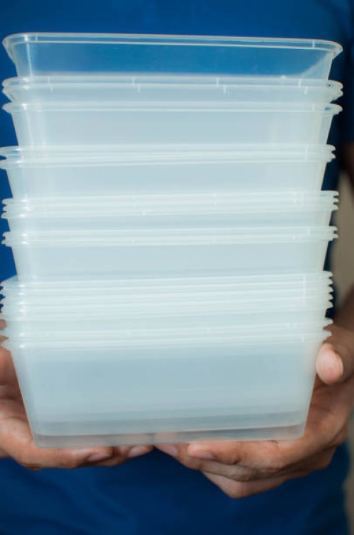 a young man is holding a recyclable plastic food container on a white background - junk food stock pictures, royalty-free photos & images