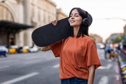 a young spanish woman with a skateboard walks down the street - fashion stock pictures, royalty-free photos & images
