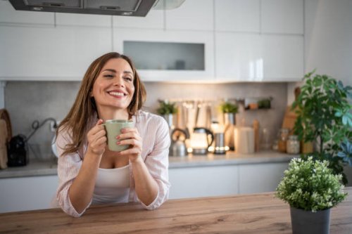 a young woman enjoys her kitchen, dressed in pajamas, drinking her morning coffee - coffee stockfoto's en -beelden