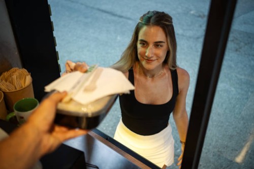 a young woman is picking up takeaway food from a food truck - junk food stock pictures, royalty-free photos & images