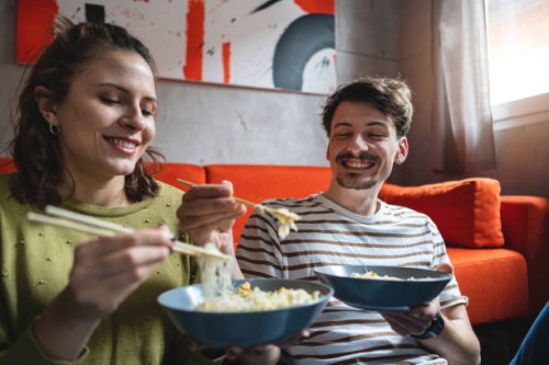 adorable young caucasian couple sharing their chinese take out food - junk food stock pictures, royalty-free photos & images