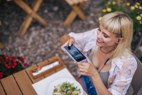 adult hipster female sitting outside in the restaurant, using a phone to take a picture of her caesar salad. - food stock pictures, royalty-free photos & images