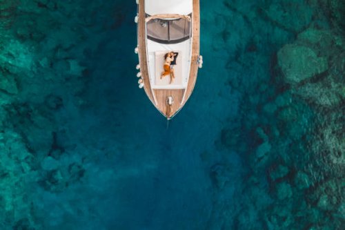 aerial drone view of couple in love on board of luxury yacht anchored in tropical paradise bay with emerald clear water - travel stock pictures, royalty-free photos & images