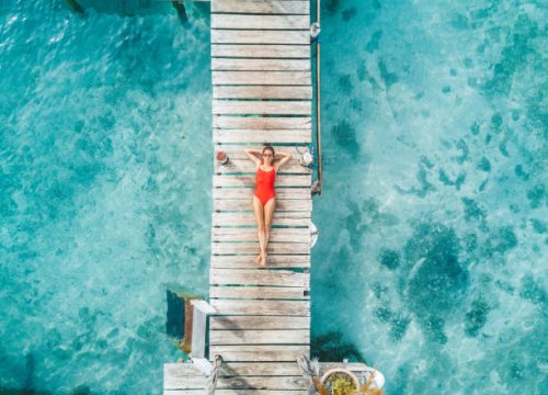 aerial shot of womann relaxing in a water bungalow - travel stock pictures, royalty-free photos & images