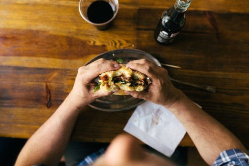 aerial view of man eating burger - junk food stock pictures, royalty-free photos & images