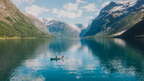 aerial view of woman and man contemplating summer in norway canoeing in the lake lovatnet - travel stockfoto's en -beelden