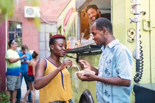 african-american couple enjoying their lunch from food truck in city street. - junk food stock pictures, royalty-free photos & images