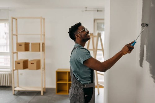 african-american professional painter paints the wall indoors - home decoration stock pictures, royalty-free photos & images