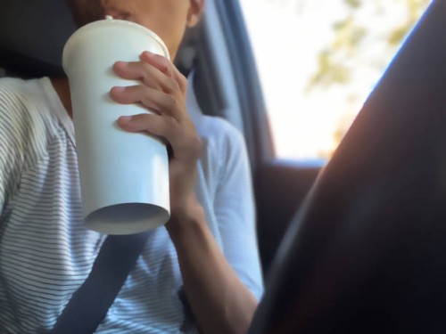 african-american woman enjoys a drink from a fast food restaurant while sitting in car behind the wheel - junk food stock pictures, royalty-free photos & images
