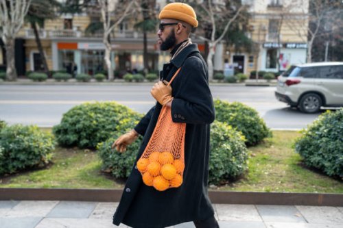 african american walking city street carrying oranges in reusable cotton mesh shopping bag - food stock pictures, royalty-free photos & images