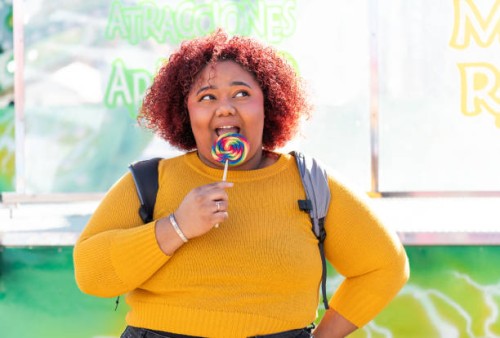 african american woman enjoying licking a rainbow candy lollipop - junk food stock pictures, royalty-free photos & images