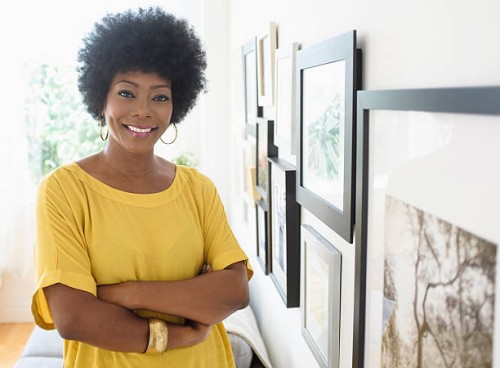 african american woman standing near pictures on wall - home decoration stock pictures, royalty-free photos & images